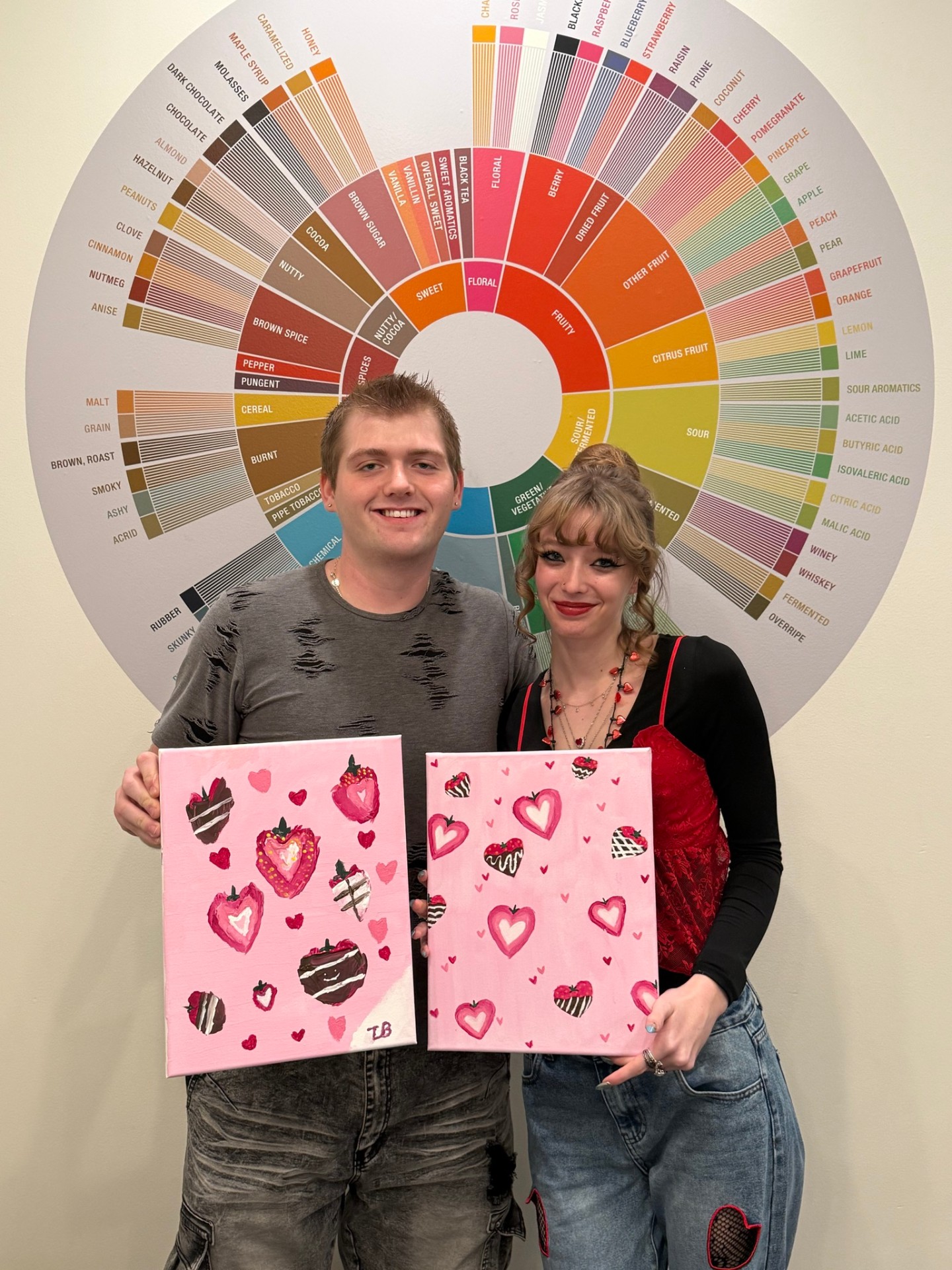 Tyler and his girlfriend Kyah holding pink strawberry paintings at Painted Leaf Studios in Boise